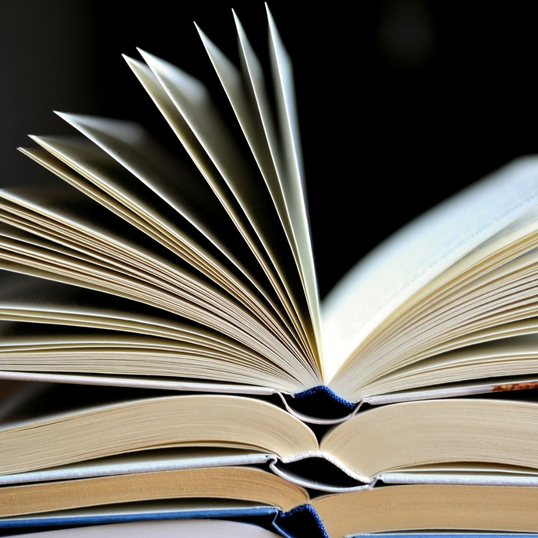 open books stacked with book on top pages fanning open 