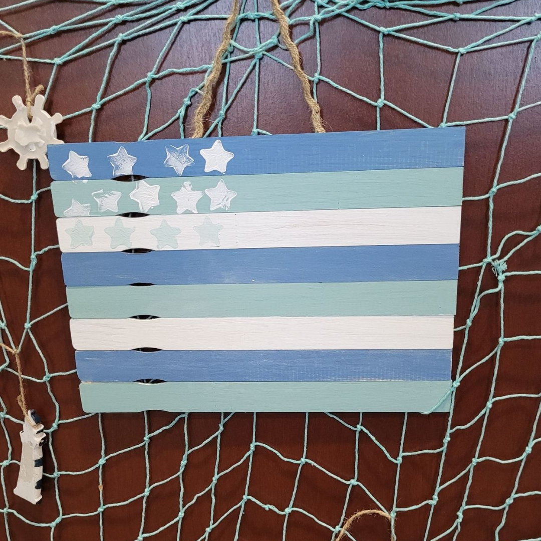 Popsicle stick flag with stars stamped in upper right corner and twine hanger in front of fishing ne