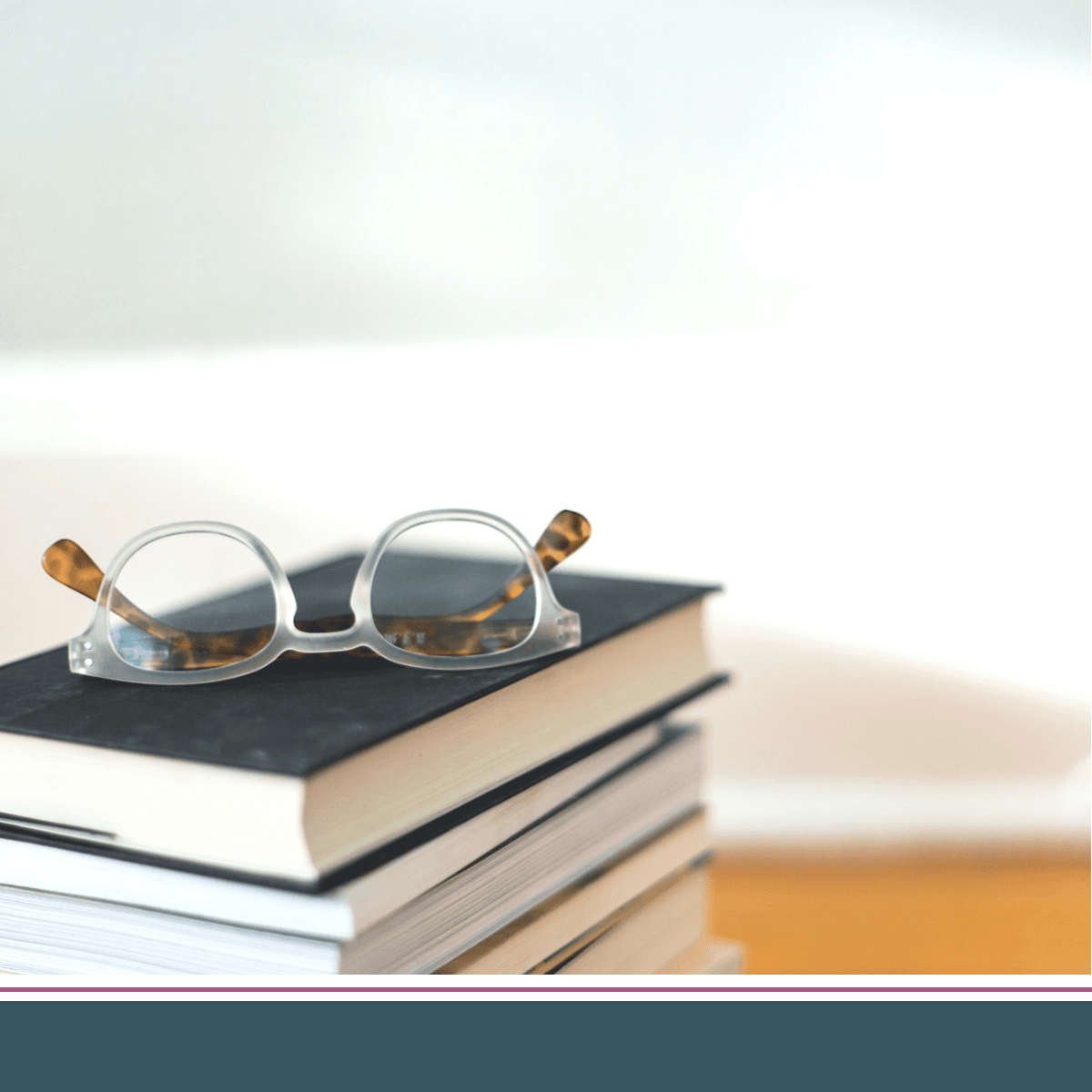 pair of eyeglasses on top of a stack of books
